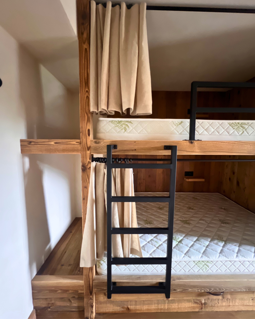 Dortoir en bois chaleureux au Gîte du Passant en Haute-Savoie, espace de repos partagé pendant la retraite immersive BYOU.